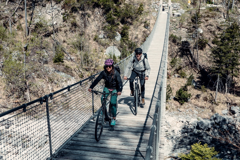 Eine Frau und ein Mann fahren mit ihrem Specialized e-Bike über eine Hängebrücke