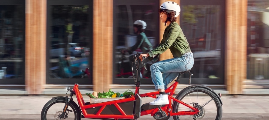 Frau transportiert ihren Einkauf im Lastenrad durch die Stadt
