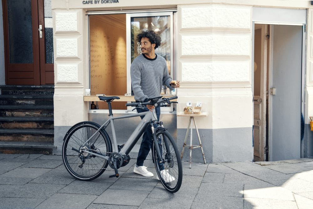 Mann holt sich einen Kaffee to go mit seinem Riese & Müller Roadster