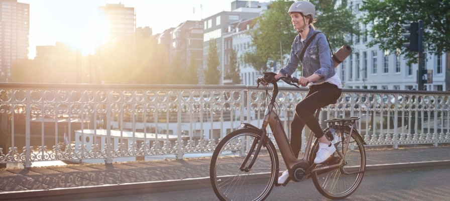 Frau fährt mit e-Bike auf einer Brücke.