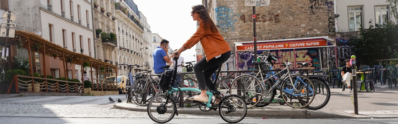 Eine Frau fährt mit einem praktischen Bromtpon Falt/Kompakt e-Bike durch die Stadt