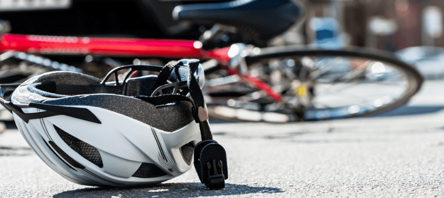 Ein Helm und ein Fahrrad liegen am Unfallort auf dem asphaltierten Boden