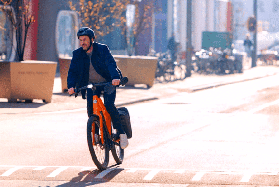 Mann fährt auf einem Orangenen Gazelle e-Bike