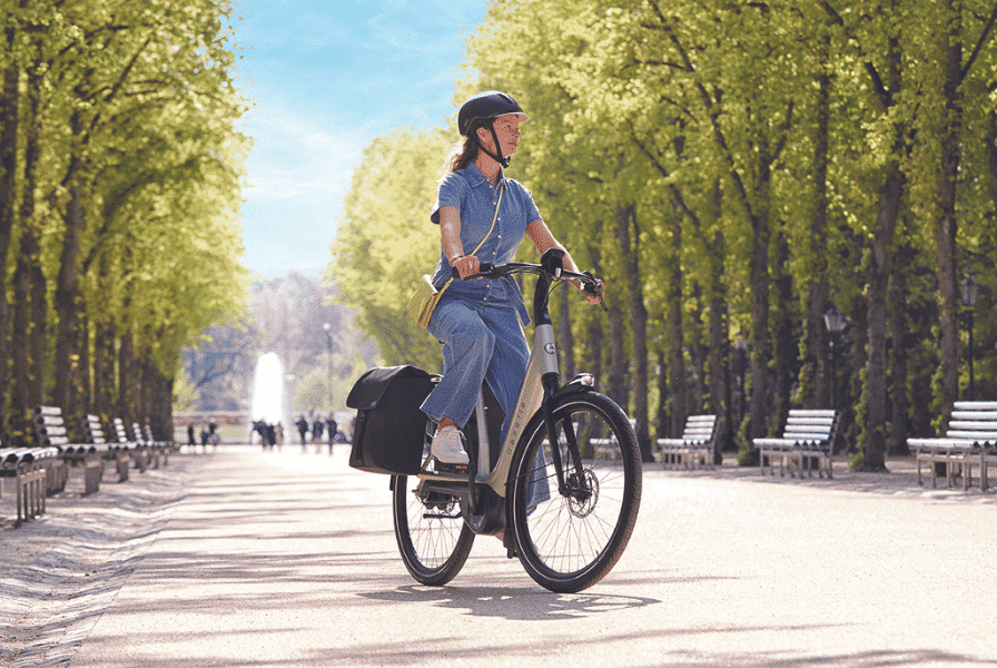 Eine Frau fährt auf einem e-Bike von Gazelle durch einen Stadtpark